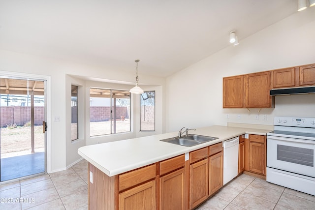 kitchen featuring white appliances, a peninsula, a sink, vaulted ceiling, and under cabinet range hood