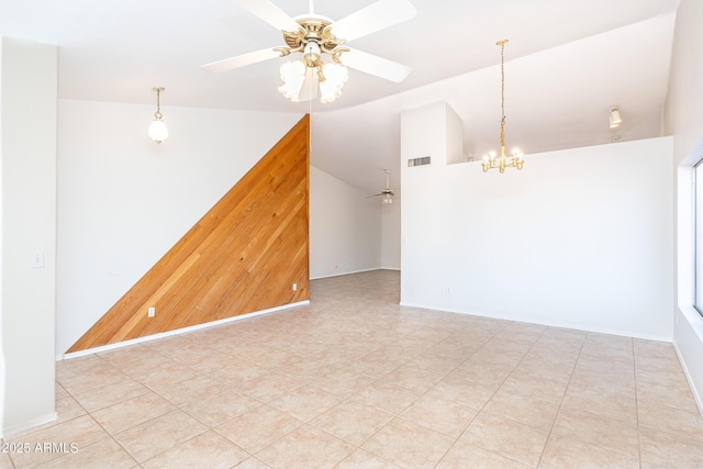 empty room with visible vents, ceiling fan with notable chandelier, wood walls, and vaulted ceiling