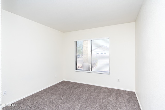 unfurnished room with dark colored carpet and baseboards