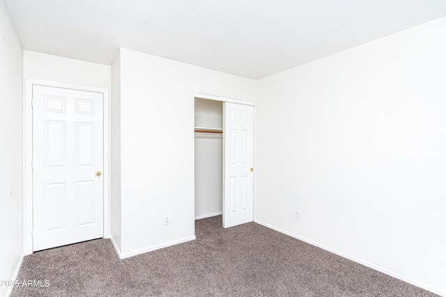 unfurnished bedroom with a closet, baseboards, and carpet