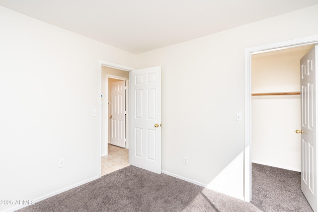 unfurnished bedroom with a closet, baseboards, and carpet floors