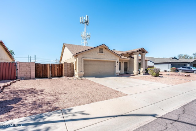 view of front of home with fence, stucco siding, a garage, driveway, and a gate