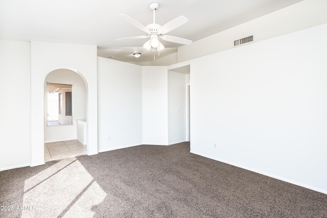 carpeted spare room featuring arched walkways, visible vents, and ceiling fan