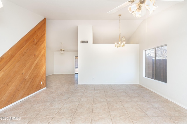 spare room with wooden walls, ceiling fan with notable chandelier, visible vents, and high vaulted ceiling