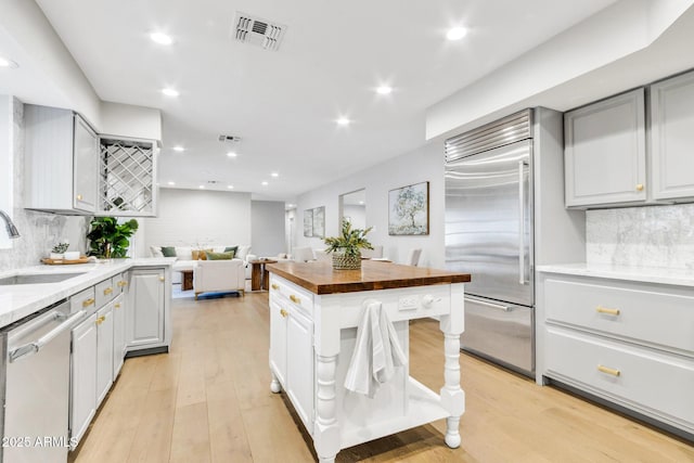 kitchen with light hardwood / wood-style flooring, stainless steel appliances, decorative backsplash, butcher block countertops, and sink