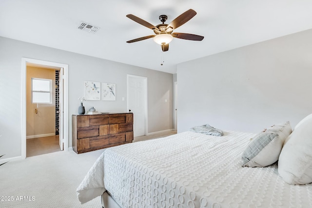 bedroom with ensuite bathroom, light colored carpet, and ceiling fan