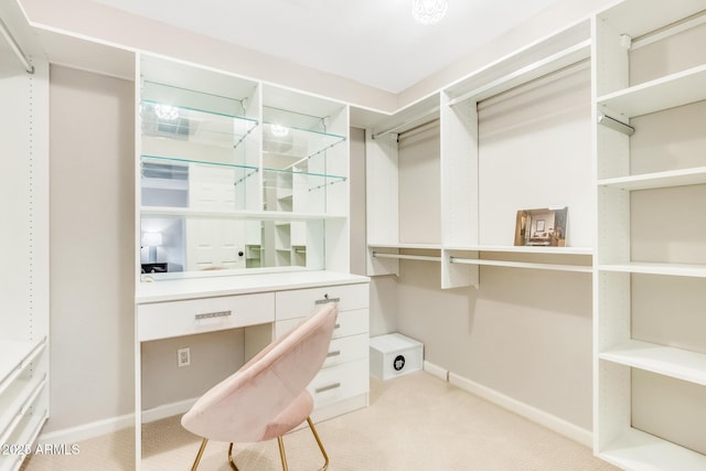 spacious closet featuring built in desk and light colored carpet