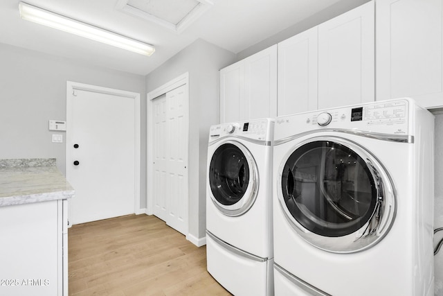 laundry area with washer and dryer, light hardwood / wood-style floors, and cabinets