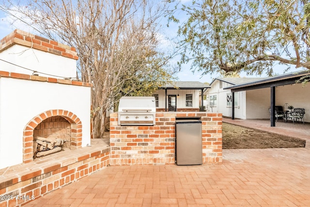 view of patio featuring an outdoor brick fireplace, area for grilling, and grilling area