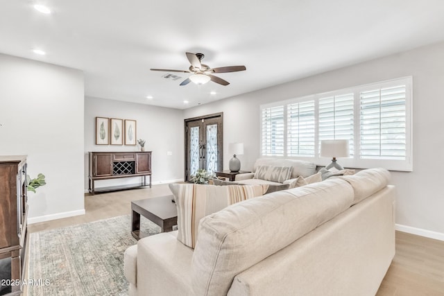 living room featuring light wood-type flooring, french doors, and ceiling fan