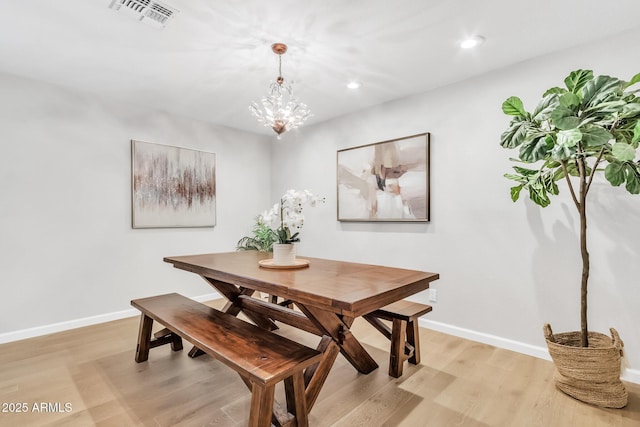 dining space with light hardwood / wood-style floors and a notable chandelier