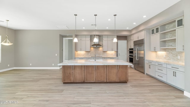 kitchen with open shelves, baseboards, a large island with sink, wall chimney exhaust hood, and a sink