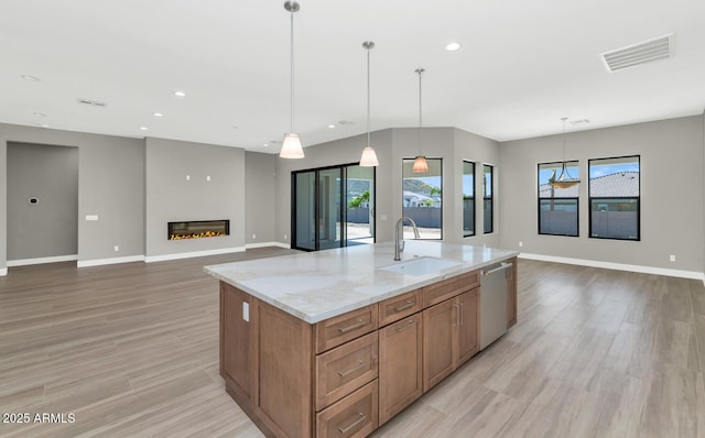 kitchen with visible vents, a sink, a glass covered fireplace, open floor plan, and dishwasher