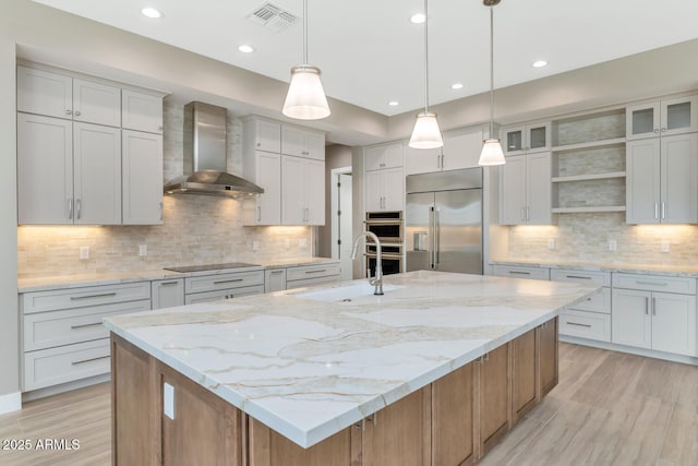 kitchen with visible vents, a sink, open shelves, appliances with stainless steel finishes, and wall chimney exhaust hood