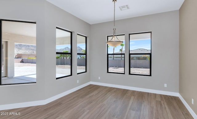 empty room with visible vents, wood finished floors, and baseboards