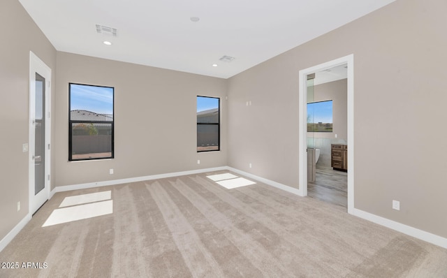 spare room with recessed lighting, plenty of natural light, light colored carpet, and baseboards