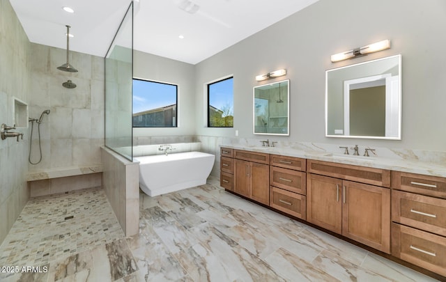 bathroom with a freestanding bath, double vanity, a walk in shower, and a sink