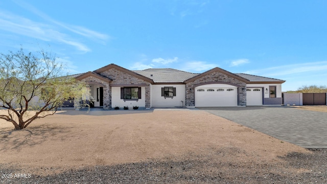 view of front of house with decorative driveway, stone siding, fence, an attached garage, and a tiled roof