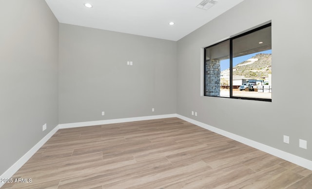 unfurnished room with light wood finished floors, visible vents, and baseboards