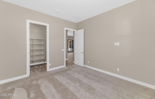 unfurnished bedroom featuring a walk in closet, carpet flooring, baseboards, and a closet