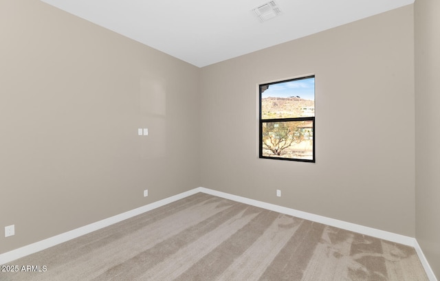 spare room with light carpet, visible vents, and baseboards