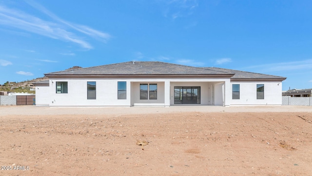 rear view of property featuring stucco siding and fence