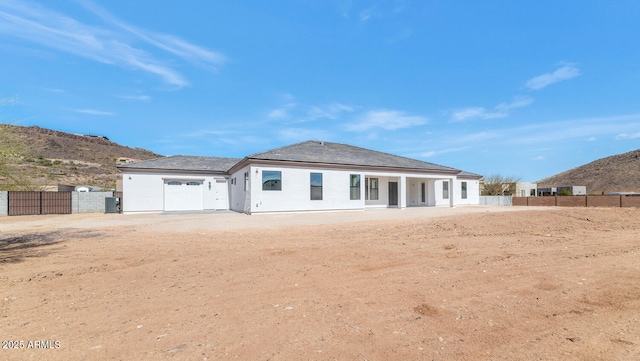 rear view of property featuring a gate, a mountain view, central AC, and fence