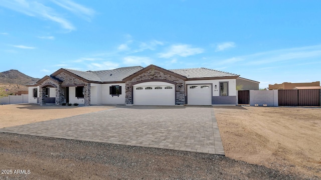 view of front facade featuring decorative driveway, a garage, stucco siding, and fence