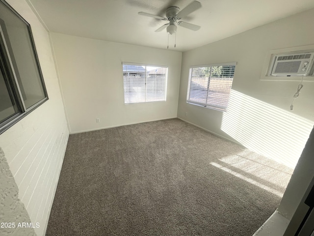 carpeted spare room featuring baseboards, a wall mounted air conditioner, and a ceiling fan