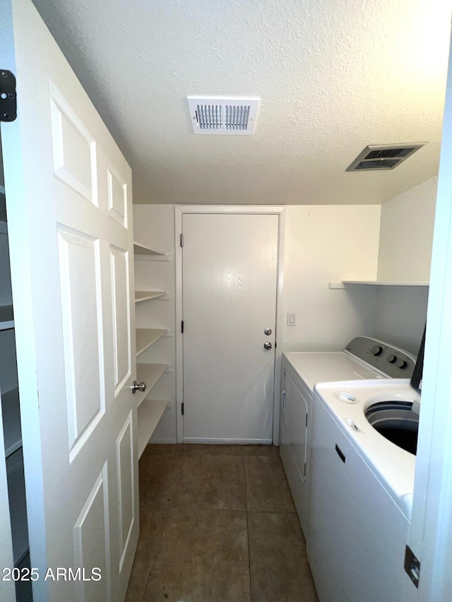 laundry area featuring laundry area, washing machine and dryer, a textured ceiling, and visible vents