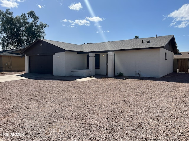 ranch-style home featuring stucco siding, an attached garage, concrete driveway, and roof with shingles