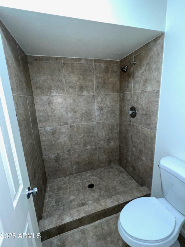 full bathroom featuring toilet and a tile shower