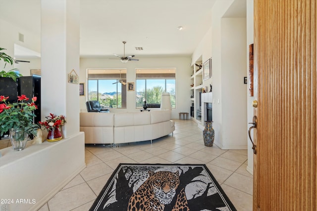 living room with ceiling fan, built in features, and light tile patterned flooring