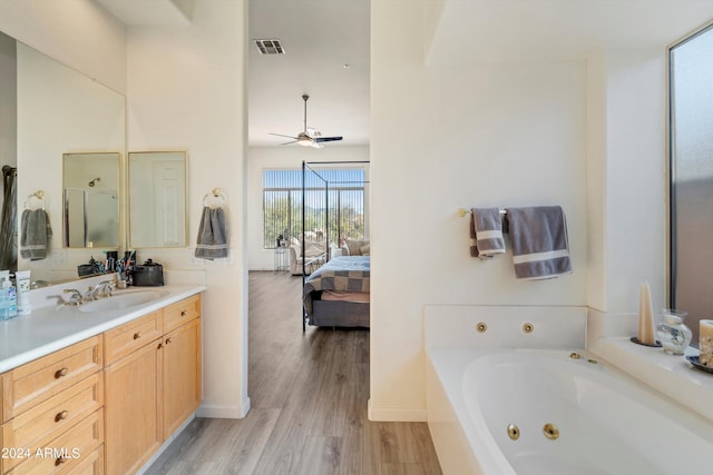 bathroom featuring ceiling fan, hardwood / wood-style floors, vanity, and a washtub