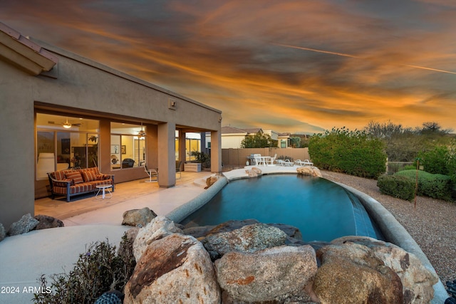 pool at dusk featuring an outdoor living space and a patio