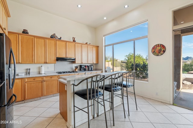 kitchen featuring a center island, light tile patterned flooring, light stone countertops, a kitchen breakfast bar, and appliances with stainless steel finishes