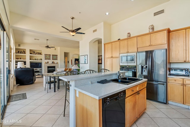 kitchen with black appliances, a kitchen bar, sink, a kitchen island with sink, and built in shelves