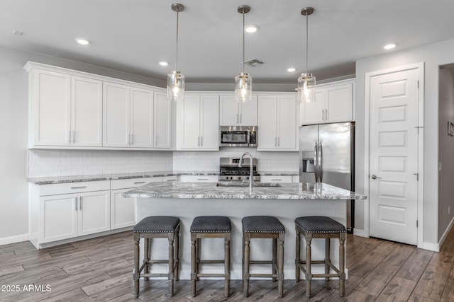 9757 E Red Giant Dr, Mesa, AZ 85212 - kitchen with stainless steel appliances, a sink, white cabinetry, wood finished floors, and recessed lighting