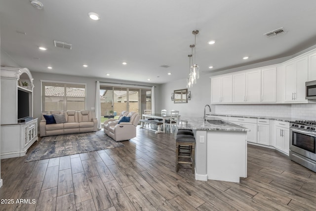 9757 E Red Giant Dr, Mesa, AZ 85212 - kitchen with appliances with stainless steel finishes, open floor plan, dark wood-style floors, a sink, and white cabinets