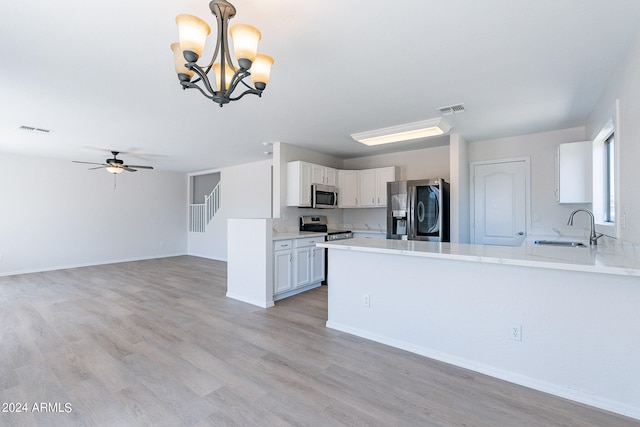 kitchen featuring sink, appliances with stainless steel finishes, light hardwood / wood-style floors, hanging light fixtures, and white cabinets