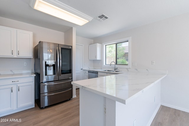 kitchen with white cabinets, kitchen peninsula, appliances with stainless steel finishes, and light hardwood / wood-style floors