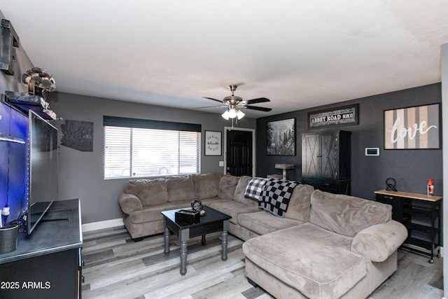 living area featuring light wood-style floors, ceiling fan, and baseboards