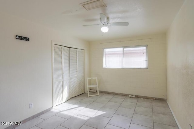 unfurnished bedroom with light tile patterned floors, ceiling fan, and a closet