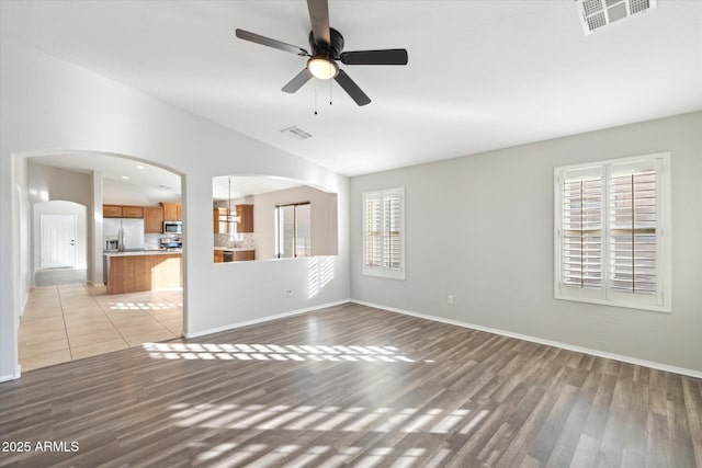 empty room featuring vaulted ceiling, ceiling fan, light hardwood / wood-style flooring, and plenty of natural light