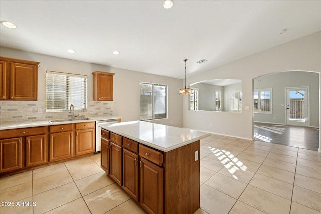 kitchen featuring dishwasher, a kitchen island, sink, hanging light fixtures, and light tile patterned floors