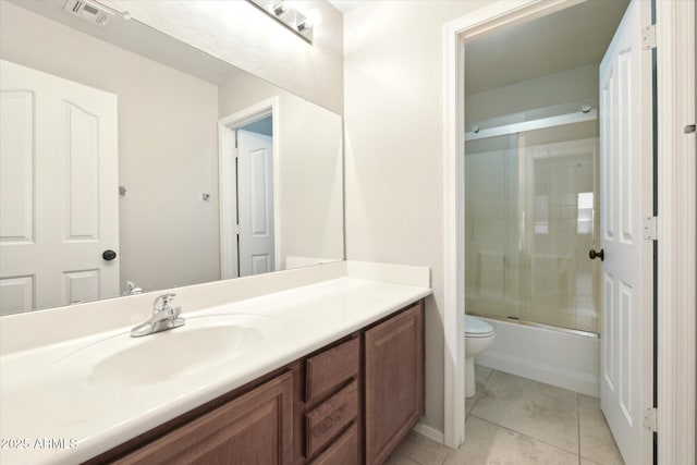 full bathroom featuring toilet, bath / shower combo with glass door, tile patterned floors, and vanity
