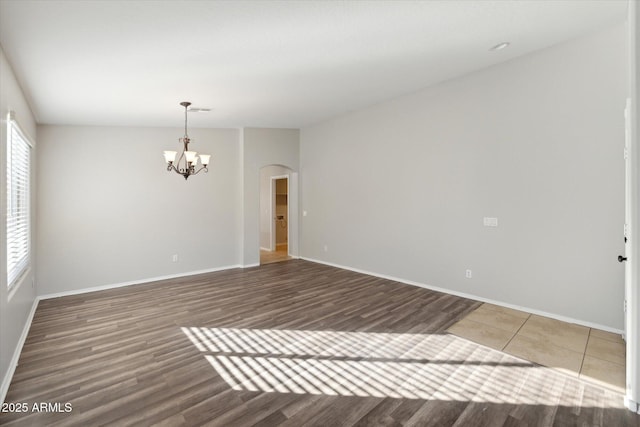 spare room featuring an inviting chandelier and hardwood / wood-style flooring