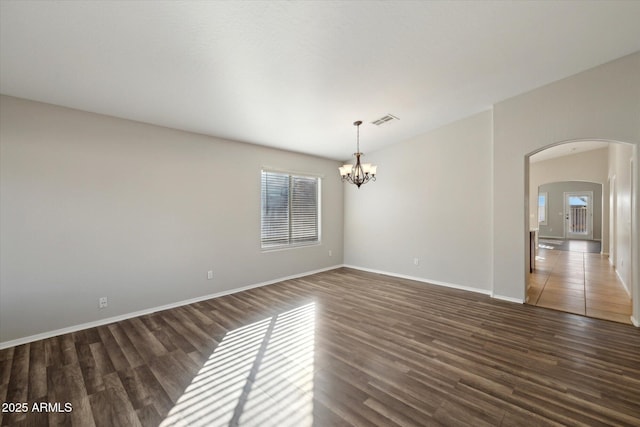 empty room featuring dark hardwood / wood-style flooring and a chandelier