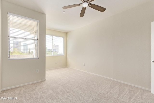 empty room featuring ceiling fan and light colored carpet