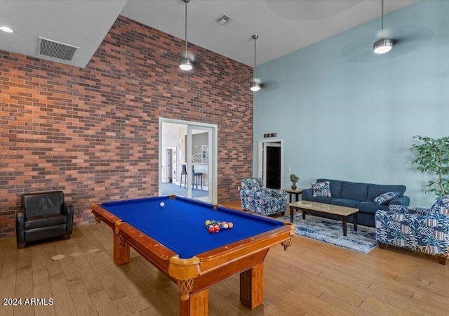 game room featuring hardwood / wood-style flooring, brick wall, a high ceiling, and pool table